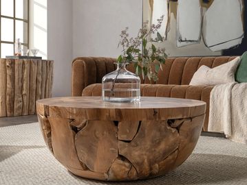 Rustic wooden coffee table with a glass vase and leafy branch in a cozy living room.