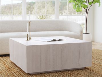 Minimalist living room with a large wooden coffee table and curved sofa.