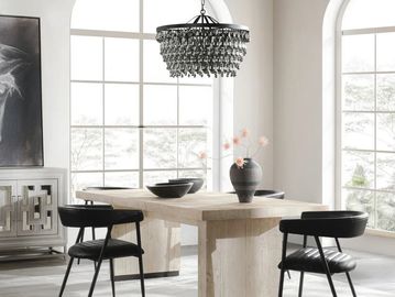 Modern dining room with black chairs and a wooden table under a crystal chandelier.