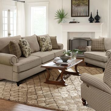 Cozy living room with beige sofas, patterned cushions, and a wooden coffee table on a textured rug.
