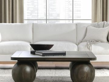 Modern living room with a white sofa and unique wooden coffee table with rounded legs.