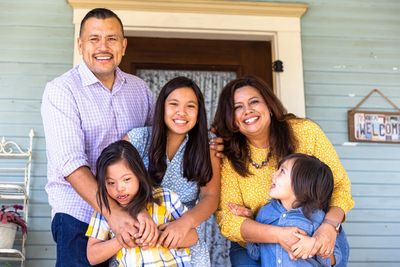 A happy family of five posing together on their porch.