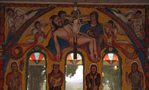 Religious mural with crucifix and saints in a chapel.