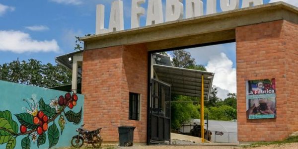 Entrance to La Fábrica coffee farm with mural and motorcycle.