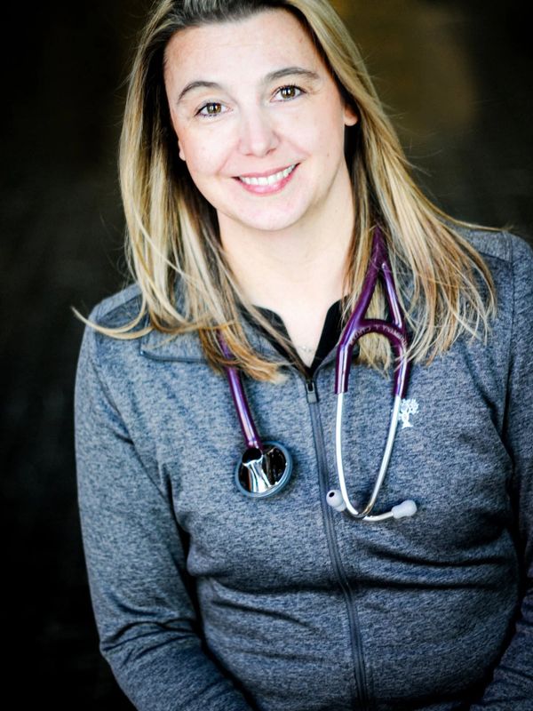 Smiling female doctor with a purple stethoscope around her neck.