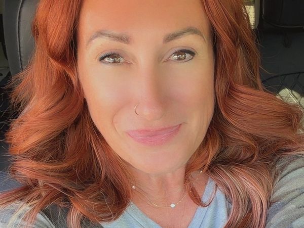 Woman with red hair smiling in a close-up selfie.