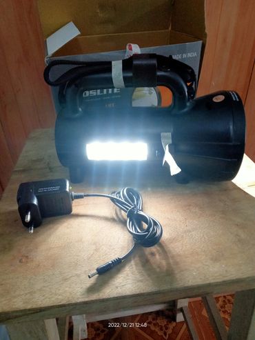 Black rechargeable LED lantern with charger on a wooden table.