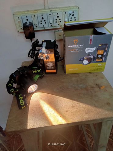 Rechargeable LED headlight with packaging on a wooden table.