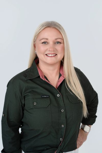 Smiling woman in a dark green shirt with long blonde hair.