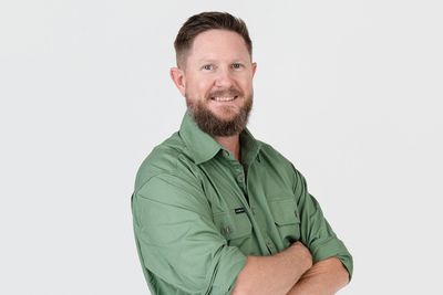 Man in green shirt with crossed arms smiling.