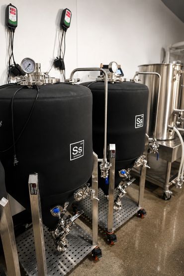 Black conical fermenters in a brewing setup.