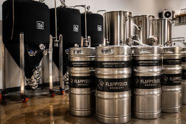 Kegs and brewing tanks inside a brewery.