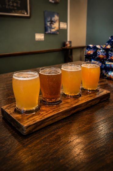 Flight of four craft beers on a wooden paddle.