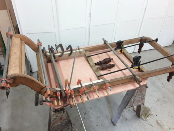 Wooden frame clamped tightly on a workbench for repair or restoration.