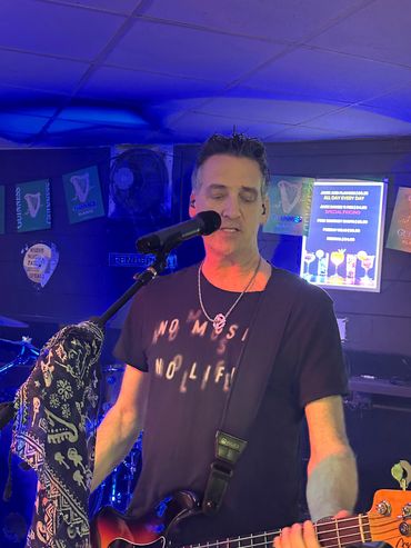 Man singing and playing guitar on stage with blue lighting.