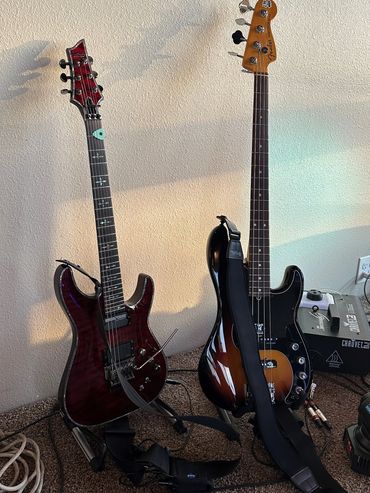 Two electric guitars standing on stands against a beige wall.