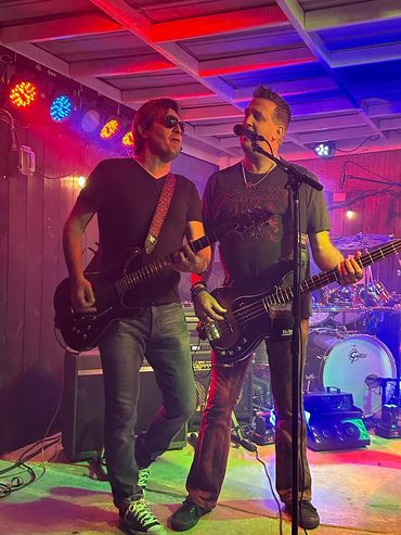 Two musicians passionately playing guitars on a colorful stage.