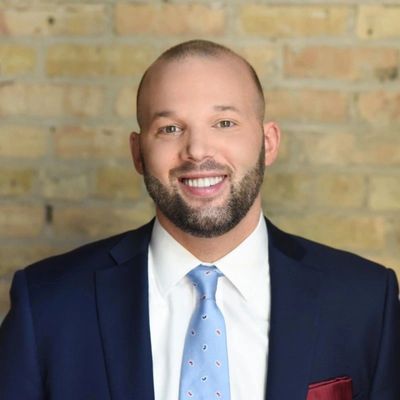 A man in a suit and tie smiling for the camera.