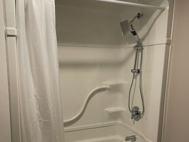 Modern white bathtub with shower and curtain in a clean bathroom.