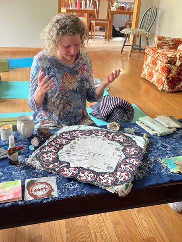 Woman sitting on floor engaged in an artistic and spiritual activity with tarot cards.