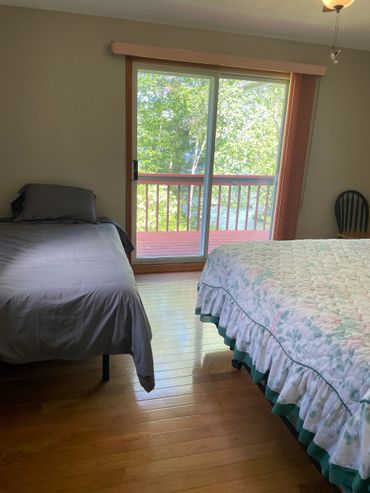 Bedroom with two beds and a sliding glass door to a balcony.