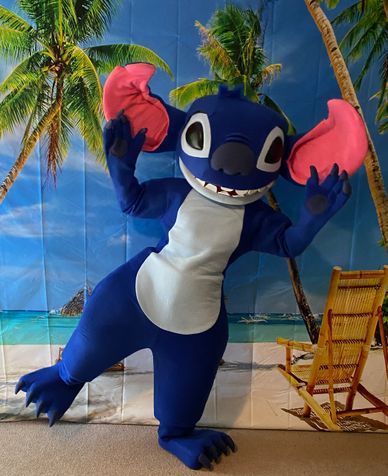 Houston mascot party character blue alien costume in front of the beach scene backdrop