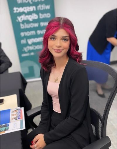 Young woman with pink hair sitting in an office chair.
