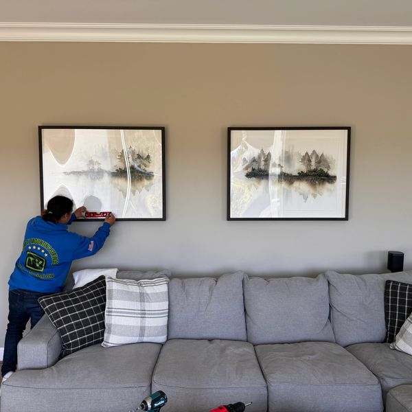 Jenae is mounting two picture frames side by side on the drywall in Bonney Lake, WA