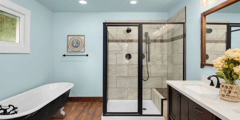 Modern bathroom with a black-framed glass shower and clawfoot tub.