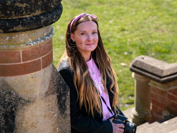 Katie Tuckwell the owner and photographer of Lavender Cloud Photography smiling, holding her camera