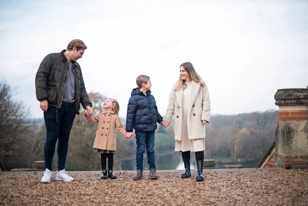 A family at Staunton country park, looking at each other smiling, wearing complimentary outfits