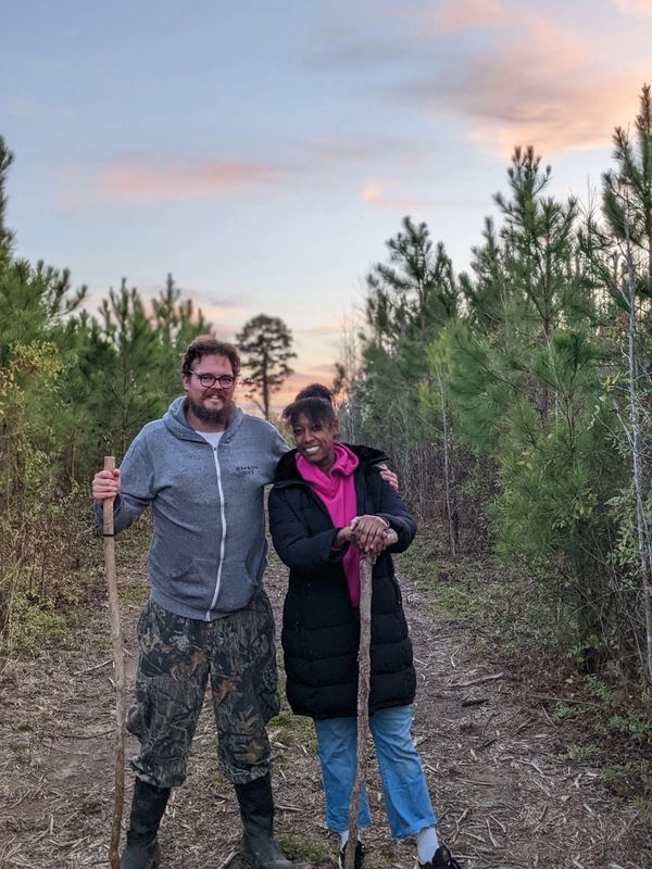 Husband and wife farmer standing in a field at sunset.