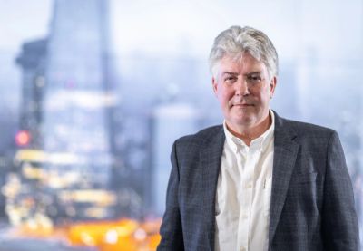 Mature man in a blazer with city backdrop.
