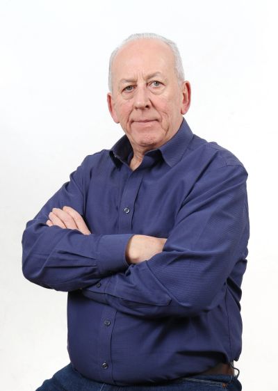 Older man posing with arms crossed.