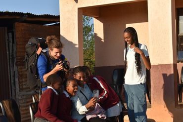 Pilot '25, Anisa '25, and Kenni-Grace '25 laugh and try out funny Snapchat filters with the children
