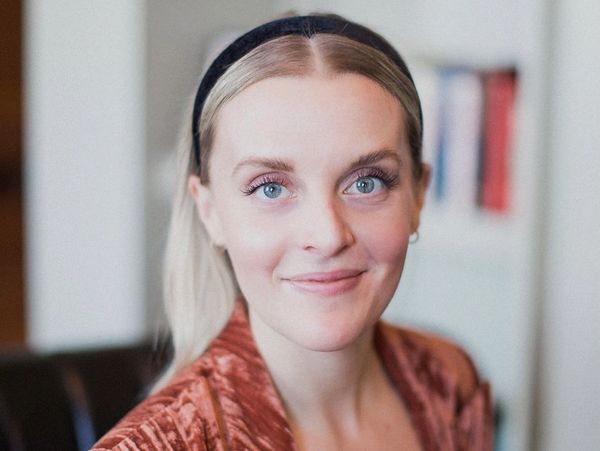 Young woman with blue eyes and a black headband smiling.