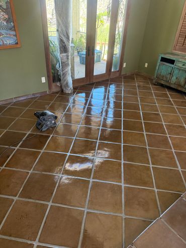 Shiny brown tiled floor reflecting sunlight near glass doors.