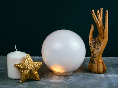 Psychic Reading represented by a crystal ball with a candle, star, and wooden hand nearby.