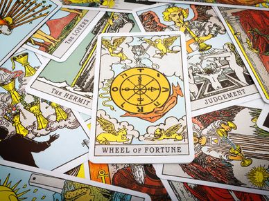 A scattered array of tarot cards showing Wheel of Fortune, Judgement, The Hermit, The Lovers card.