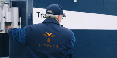 A worker in a TraRock uniform opening a truck door.