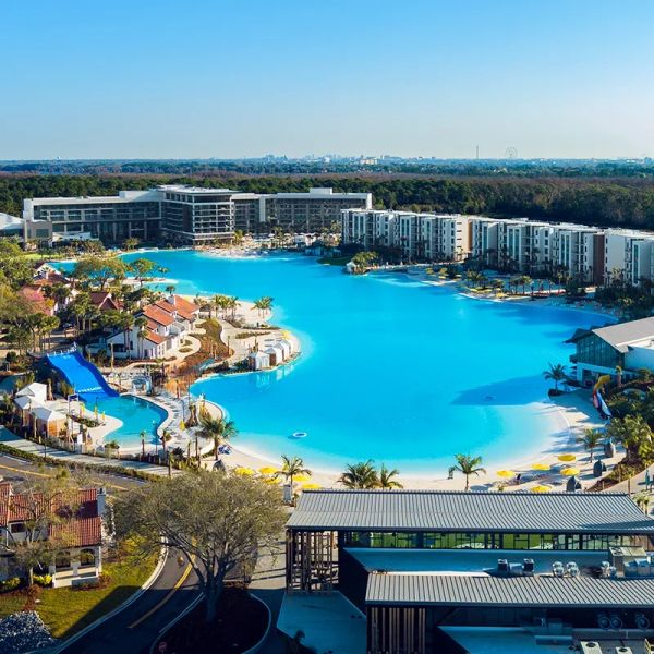 A large resort with a massive artificial pool surrounded by buildings and palm trees.
