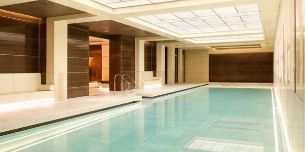 Modern indoor swimming pool with warm lighting and wood accents.