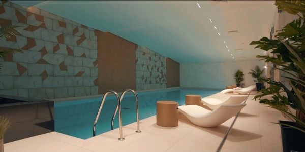 Indoor pool area with modern lounge chairs and geometric wall design.