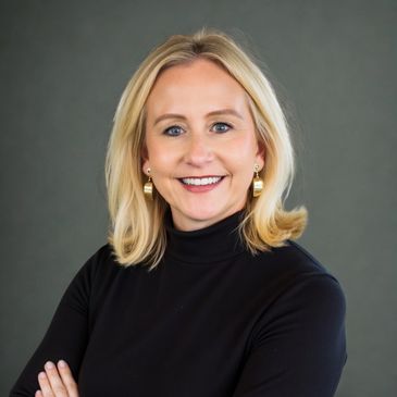 Professional woman with blonde hair and gold earrings in a black turtleneck.