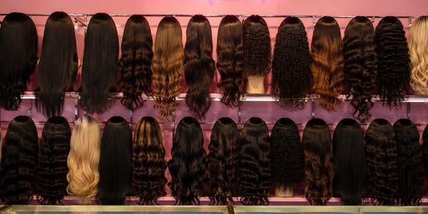 Rows of various wigs displayed on mannequin heads.