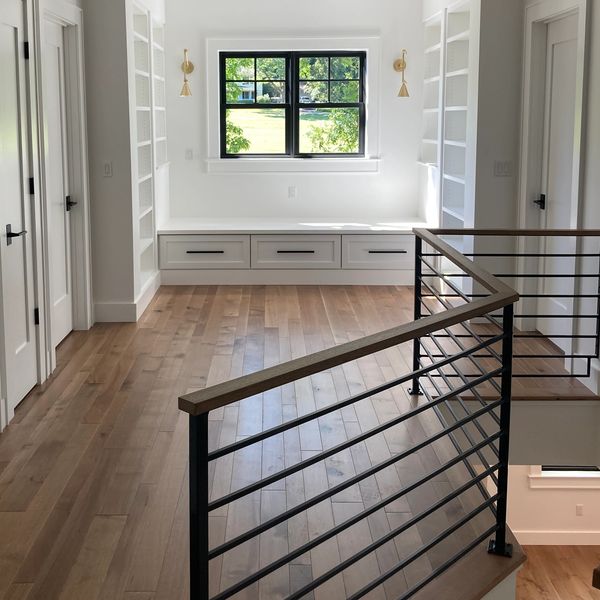 Modern bright hallway with wood floors, custom steel railings and built-in window seat.
