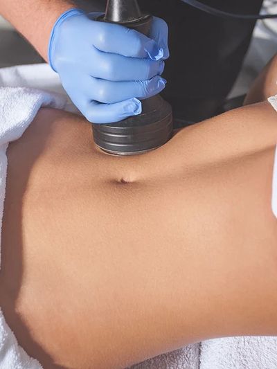 A person receiving a body treatment with a handheld device on the abdomen.