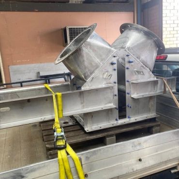 Large metal duct component secured in a truck bed.