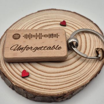 Wooden keychain with Spotify code and 'Unforgettable' text on a wooden round base with small red hearts.