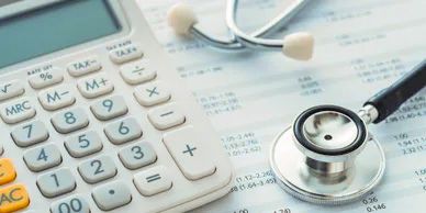 A doctor's stethoscope rests on an account report next to a calculator.